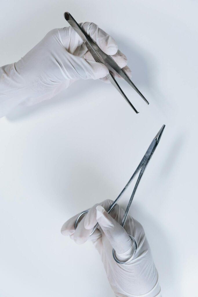 Detailed close-up of two hands holding surgical forceps over a white background.